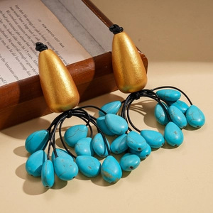 Ethnic drop earrings with turquoise beads and golden studs over vintage book backdrop