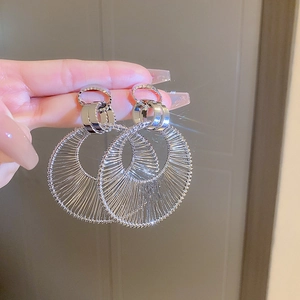 Close-up of hand holding silver mesh flower tassel earrings with intricate woven texture