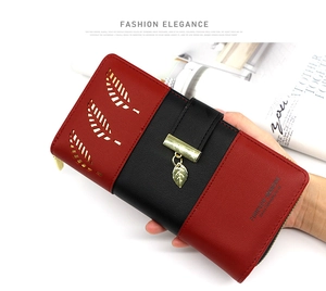 Detail of bicolored PU leather wallet with hollow leaf design and gold leaf pendant