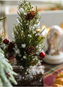 Macro shot of mini Christmas tree with red berries, pinecones and snowy wood base