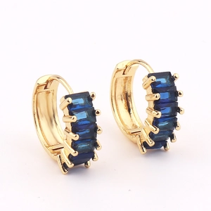 Detail view of gold hoop earrings set with emerald-cut dark blue zirconia stones