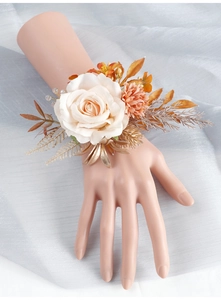 Détail du corsage de poignet de mariée avec rose en soie crème et feuilles dorées