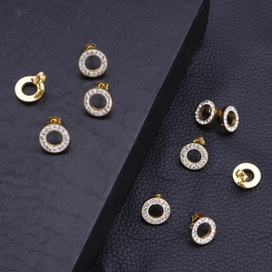 Close-up of gold hollow round earrings with sparkling crystals on black leather texture