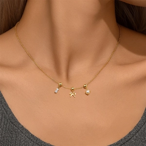 Close-up of a gold S925 silver necklace with pearl, crystal bar, and bow pendants on a model
