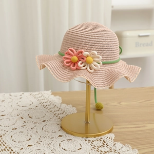 Close-up of woven straw sun hat with crochet flower details and scalloped brim edges