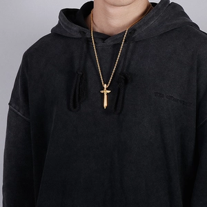 Détail d'un collier avec pendentif épée et ailes dorées sur le cou d'un mannequin