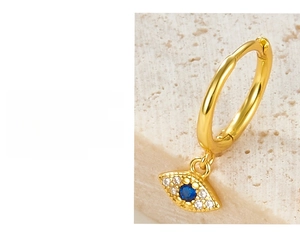 Macro view of gold Evil Eye pendant earring featuring blue stone and white rhinestones
