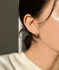 Close-up of minimalist sterling silver oval hoop earrings worn on a model's ear