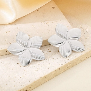 Macro detail of silver plumeria flower stud earrings with ridged texture on petals