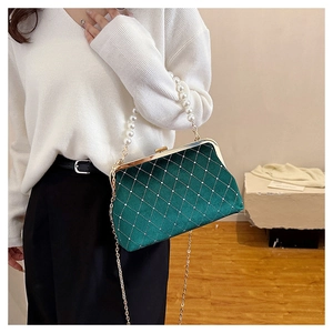Detail of dark green velvet shell bag with diamond patterns and pearl handle strap