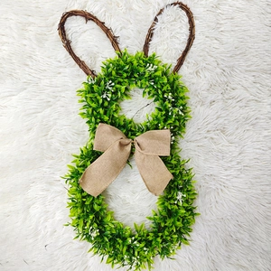 Detail of bunny easter wreath with green faux leaves, rattan ears and burlap bow