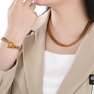 Ensemble collier et bracelet maille gourmette dorée pour homme avec costume beige