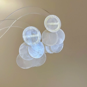 Detail of round shell tassel earrings with white translucent discs and soft luster
