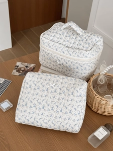 Close-up of quilted floral cosmetic bags set with delicate bow detail and handle