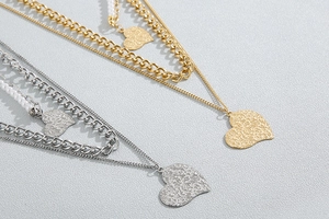 Detail of layered gold and silver titanium steel necklaces with heart pendants and pearls