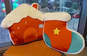 Detail of plush house and Christmas stocking pillows on a leather chair