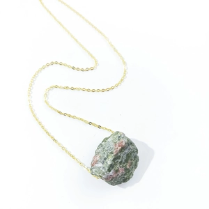 Detailed close-up of a gold chain necklace featuring a natural unakite gemstone pendant