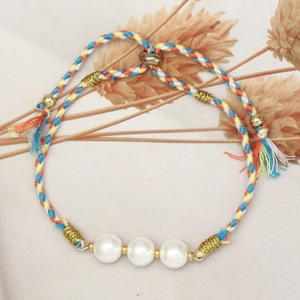 Detail of colorful woven bracelet with white glass pearls and golden accents