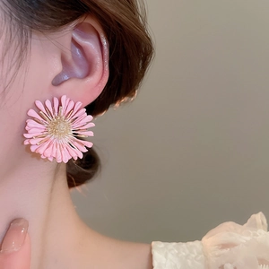 Close-up of pink raffia daisy stud earring worn on model for summer beach vacation