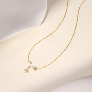 Detailed view of gold necklace with pearls, zircon pendant and sparkly star charm