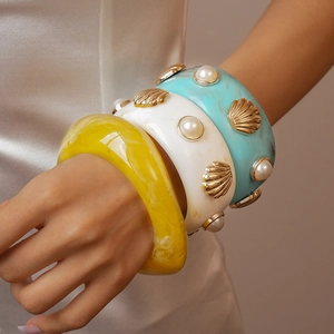 Detail of resin bangle set with faux pearls and metal shells in summer ocean style
