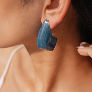 Close-up of blue marble resin geometric earrings on model showing size and texture