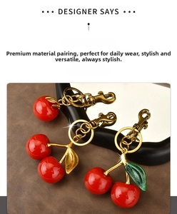 Detailed view of glossy red cherry resin pendants with golden metal leaf accents and clasps