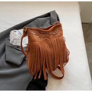 Detailed view of a brown suede crossbody bag with fringe and embroidered geometric patterns
