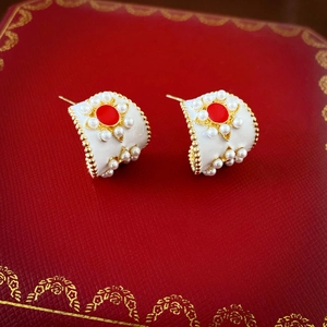 Détail des boucles d'oreilles rétro en émail en forme de C avec perles sur écrin rouge