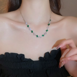 Detail view of silver necklace with green rectangular and clear square zircon stones