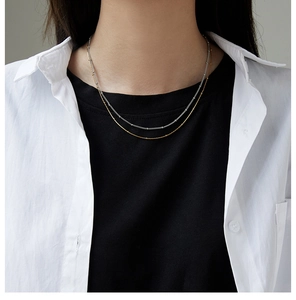 Close-up of layered gold and silver bead necklaces on model highlighting textures
