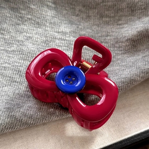 Nahaufnahme der roten Essigsäure-Haarklammer mit blauem Knopf und goldener Metallfeder