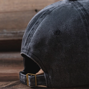 Detailed close-up of charcoal gray washed cotton baseball cap with adjustable metal buckle