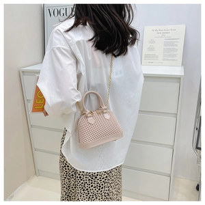 Pink jelly shell bag with woven texture and gold chain strap shown on a model
