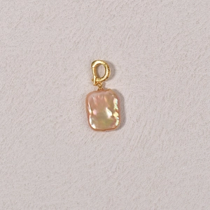 Detail of a natural baroque pearl pendant with pink-gold luster and golden metal clasp