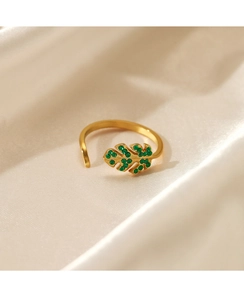 Macro detail of leaf-shaped gold ring with green zircon stones on white silk