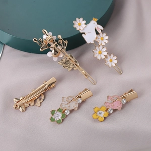 Detailed view of rabbit and flower hair clips with enamel and rhinestones on purple fabric