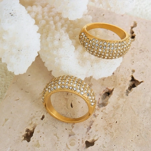 Elegant gold titanium steel ring with paved Czech diamonds on textured stone background