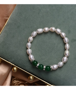 Detailed view of baroque pearls and green agate beads on a green velvet jewelry box