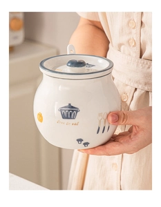 Detail of white ceramic storage jar with blue patterns and love to eat text in hand