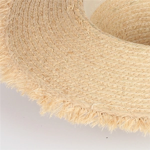 Close-up of handmade raffia sun hat showing detailed spiral weave and frayed fringe edges