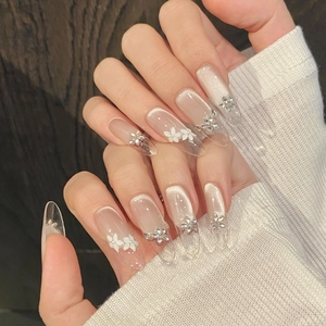 Close-up of cat-eye nails with 3D white flower motifs and shimmering rhinestone accents