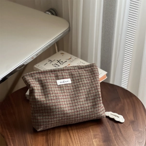 Macro view of retro plaid wool makeup bag with Simple Wish label on wooden stool