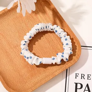Close-up of a white polka dot scrunchie on a wooden tray with soft lighting