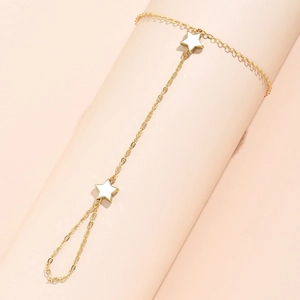 Golden 14K chain hand harness with white five-pointed stars on a soft pink background