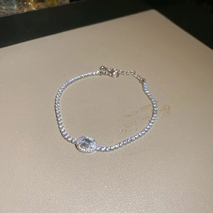 Close-up of silver tennis bracelet featuring an oval zircon center and halo setting
