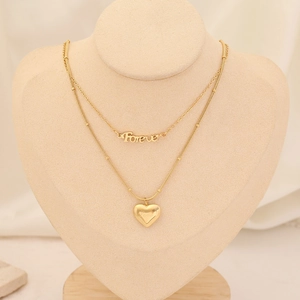 Detail of layered gold necklace featuring a Forever pendant and a heart-shaped charm
