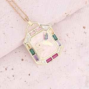Macro view of octagonal gold pendant featuring a hummingbird and colorful zircon stones