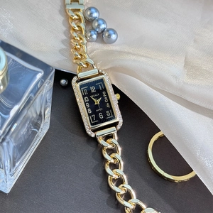 Macro view of a rectangular gold-tone watch with crystal bezel and Cuban chain band