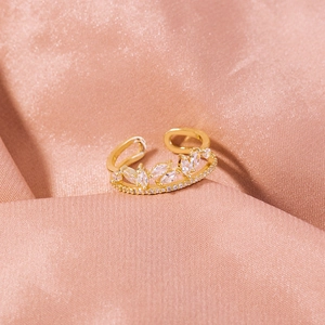 Detail of adjustable gold ring with marquise-cut zircons on pink silk background
